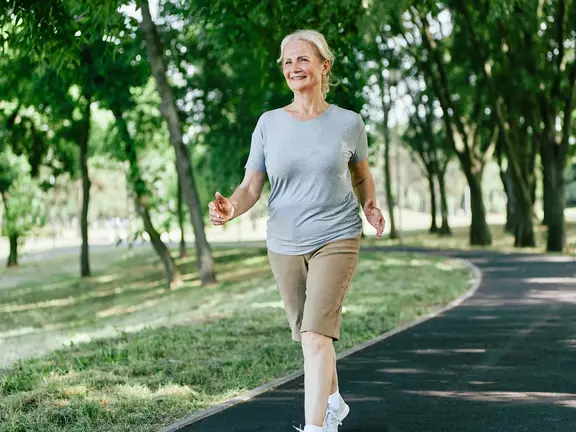Aktive ältere Dame beim Spaziergang in der Natur, symbolisch für den Erhalt der Beweglichkeit trotz Arthrose im Alter.