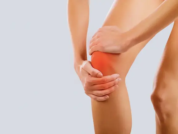 Frau hält sich das Knie aufgrund von Gelenkschmerzen - ein häufiges Problem bei Arthrose