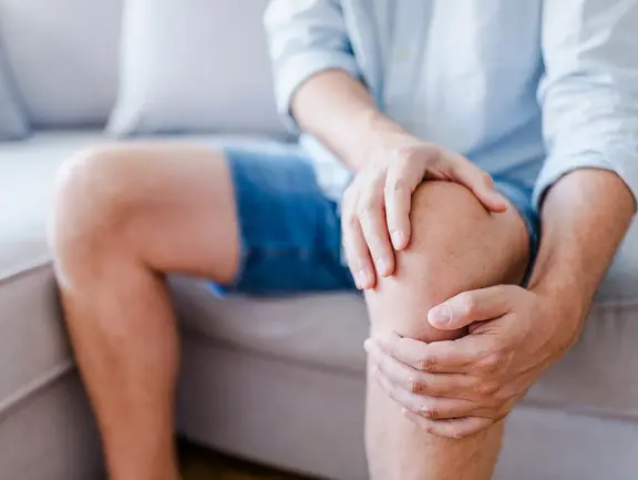 Mann hat Schmerzen beim Aufstehen: oft Anzeichen einer Arthrose